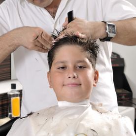 Friseur schneidet Haare eines Jungen